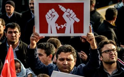 Kalem tutan ve zincirlerini kıran ellerin olduğu pankartı tutan vatandaş