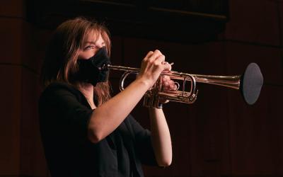 maskeyle trompet çalan bir kadın