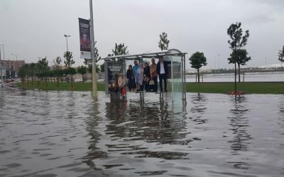 Sel basmış yolda otobüs durağında oturakların üstüne çıkmış insanlar