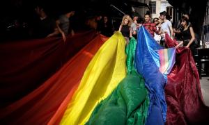 Aktivistler LGBTİ+ bayrağını kaldırıyor.
