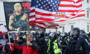 Bir elinde Rambo şeklinde fotomontajlanmış Trump fotoğrafının olduğu, diğer elinde "Make America Great Again" yazılı bayrak taşıyan ABD'li şahıs