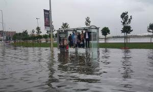 Sel basmış yolda otobüs durağında oturakların üstüne çıkmış insanlar