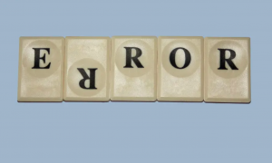 Yatay dikdörtgen şeklindeki görselde açık lacivert bir arkaplan ve Scrabble taşları ile ERROR kelimesi yazıyor, ancak R harfi ters yazılmış.